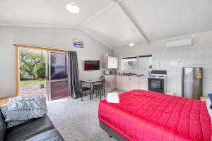 罗托鲁瓦Jack & Di's Lakefront Motel的一间带红色床的卧室和一间厨房