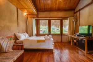 枚州县Mai Chau Onsen Retreat的一间卧室配有一张床、一张沙发和一台电视
