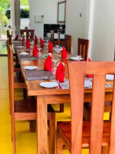 蒂瑟默哈拉默Yala River Front Hotel & Restaurant的一张长木桌,上面有红色的餐巾