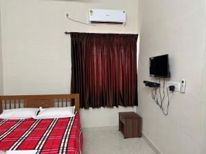 马杜赖Jothi Residency的一间卧室配有一张床、一台电视和一个窗口