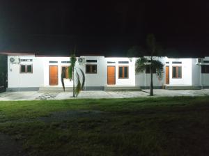 DondoHome Syariah Guest House Ampana的白色房子,晚上有橙色门