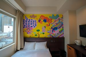 大阪Lub d Osaka Honmachi的卧室配有一张床,墙上挂有绘画作品