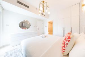 迪拜Charming Brand New 2BR close to the Beach的白色卧室设有一张大床和镜子