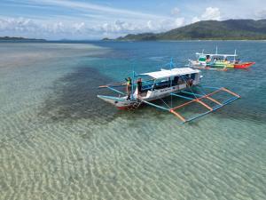 圣维森特PORT BARTON ISLAND HOPPING TOUR MjYohann Boat的两个人站在水中船上