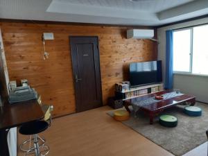 木曾町Takumisou1的客厅设有木墙、电视和桌子
