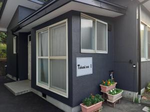 木曾町Takumisou1的一间黑色房子,有两个窗户和两个盆栽植物