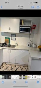 悉尼Bondi accomodation的厨房配有白色橱柜和微波炉