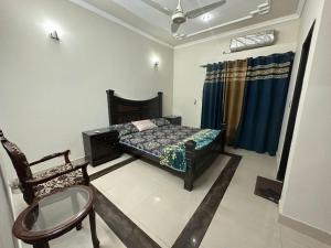 拉合尔Bahria Town - 10 Marla 2 Bed rooms Portion for families only的一间卧室配有一张床和一把椅子