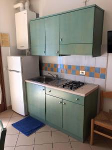 洛萨皮内塔Enjoy your stay in our nice flat with pool的厨房配有绿色橱柜、水槽和冰箱。