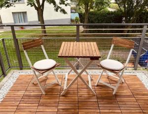 舍讷费尔德Gemütliche Wohnung mit Balkon in Schönefeld的甲板上配有两把椅子和一张木桌