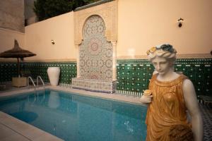 非斯Riad Fes Ziyat & Spa的站在游泳池旁的女人雕像