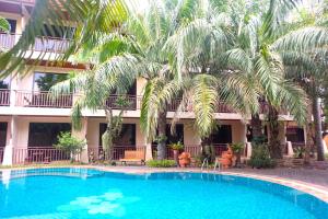 北芭堤雅泰国普拉度假酒店的棕榈树建筑前的游泳池