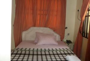 阿沙巴Room in Lodge - Vision Serviced Apartments的一张带橙色窗帘的床和两个枕头
