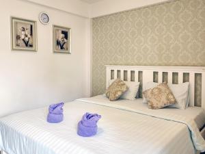 Ban Map KhlaPhureya Ville的客房内的两张床,配有紫色毛巾
