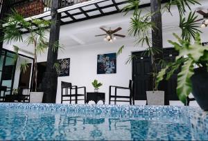 清莱The Courtyard Chiangrai的一个带椅子和吊扇的客房中的游泳池