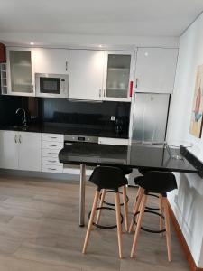 波瓦-迪瓦尔津Beach House的厨房配有白色橱柜、黑桌和凳子