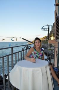 切法卢MiraMare Residence Cefalú的坐在水边桌子上的女人