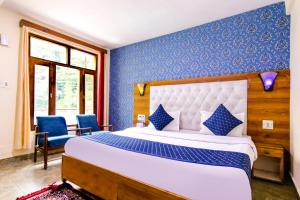 马拉里FabHotel Negis Shivalay的一间卧室配有一张带蓝色墙壁的大床