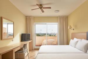 雷塔马尔ALEGRIA Cabo De Gata的配有一张床、一张书桌和一扇窗户的酒店客房