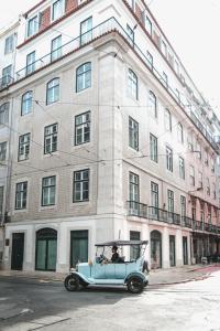 里斯本The House on the Pink Street in Lisbon的停在大楼前的旧蓝色汽车