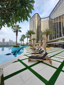 澳门YOHO Treasure Island Hotel的酒店游泳池旁的一排躺椅