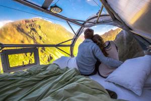 乌鲁班巴冒险套房天空旅馆的一对夫妇坐在帐篷里,眺望着群山