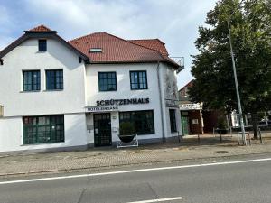 沃尔夫斯堡Hotel Schuetzenhaus Vorsfelde的街道边的白色建筑