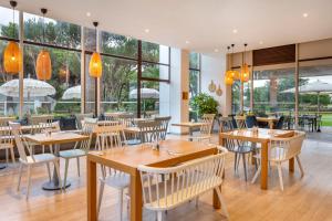 金塔湖Vilar do Golf的餐厅设有木桌和椅子以及大窗户。