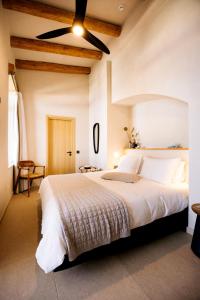 米尔希奥斯Mirthea Suites的卧室配有一张白色大床和吊扇