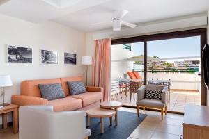 阿德耶日落湾俱乐部钻石度假公寓的一间带橙色沙发的客厅和一个阳台