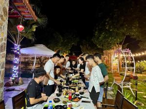 巴位Homestay Bài Văn garden的一群人站在桌子旁吃着食物