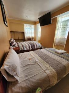 阿亚库乔Hostal Capac的一间卧室配有两张床和一台平面电视