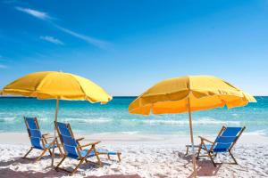 德斯坦桑德斯丁海滩希尔顿高尔夫Spa度假酒店的海滩上的两把椅子和两把遮阳伞