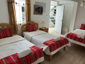 库斯科Hotel Plateros的一间卧室配有两张带红白毯子的床