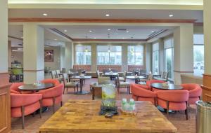 拉勒米拉勒米希尔顿花园旅馆的餐厅设有橙色椅子和桌子以及窗户。