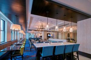 路易斯威尔路易维尔市中心希尔顿合博套房酒店的用餐室配有桌椅和吊灯。