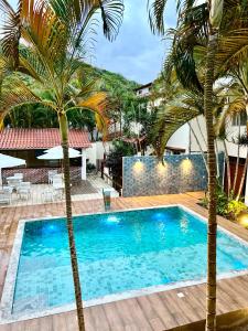 阿拉亚尔-杜卡布Pousada Estalagem dos Corais da Prainha的一座房子前面的游泳池,两棵棕榈树