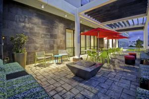 什里夫波特Home2 Suites By Hilton Shreveport的一个带桌椅和红色遮阳伞的庭院