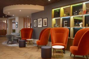 博勒姆伍德DoubleTree by Hilton London Elstree的一间备有橙色椅子和桌子的等候室