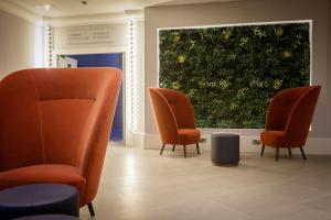 博勒姆伍德DoubleTree by Hilton London Elstree的一间设有橙色椅子和大窗户的等候室