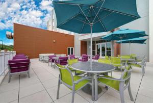 马纳萨斯Hilton Garden Inn Manassas的庭院配有色彩缤纷的桌椅和遮阳伞