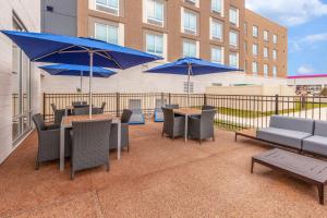 布卢姆菲尔德山Hampton Inn & Suites Bloomfield Hills Detroit的一个带桌椅和蓝伞的庭院