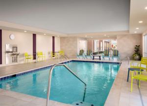 图珀洛Home2 Suites By Hilton Tupelo的游泳池位于酒店客房内,配有桌椅