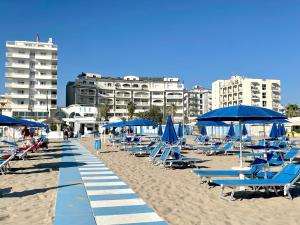 里米尼Yes Hotel Touring & SPA的海滩上摆放着蓝色沙滩椅和遮阳伞