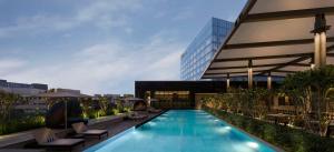 班加罗尔Hilton Bengaluru Embassy Manyata Business Park的一座带躺椅的游泳池和一座建筑