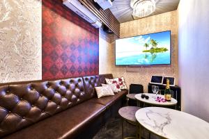 大阪Hotel Bali An Resort Shinsaibashi的一间酒吧,配有棕色皮沙发和两张桌子