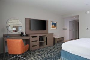 马尼斯蒂Hampton Inn & Suites Manistee, Mi的酒店客房配有一张床和一张书桌及一台电视