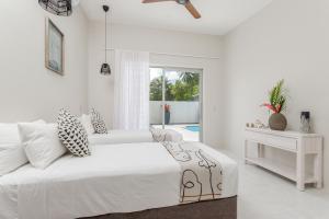 拉罗汤加Villa Varia的一间白色卧室,配有床和游泳池