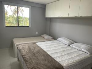 伊波茹卡Flat Confort Pé na Areia的一间卧室设有两张床和窗户。