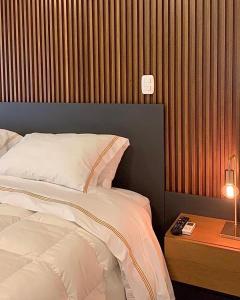 格拉玛多Austin Suites Gramado的一间卧室配有一张床和一张带台灯的桌子
